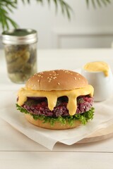 Tasty vegetarian burger with beet patty on white wooden table