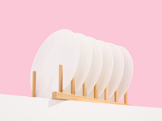 White plates stand in a wooden dish rack. Luxury minimal tableware.