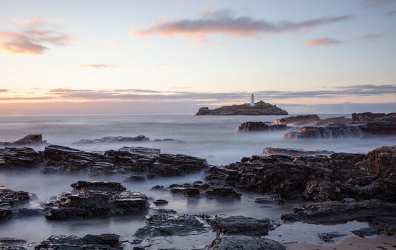Sunset photograph of the rocky shores near the lighthouse at Godrevy, Cornwall.