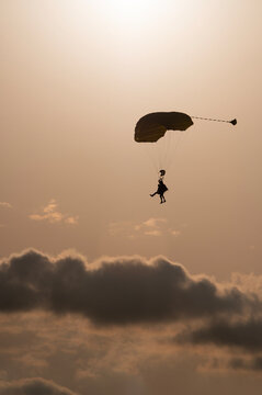 Vertical image of a silhouette of a tandem of parachuters with some dark clouds as background