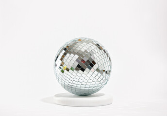 A beautiful bright shining disco ball on a round white stand. Night disco party.