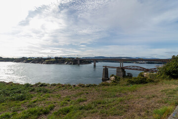 Bridging the Gap: A Scenic View of a Bridge Over a River Under a Cloudy Sky