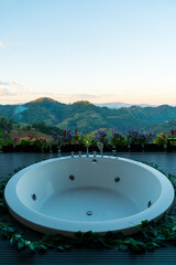 Fototapeta na wymiar bath tub on balcony with mountain hill background