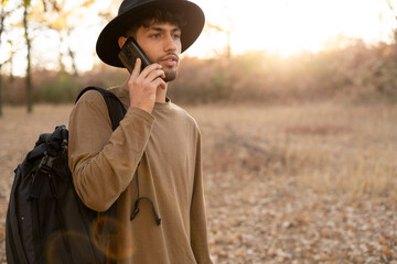 Arabic man in a hat hiking in nature uses a mobile phone making a call