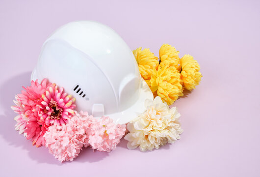 White head protection helmet and summer beautiful bright colorful flowers on a purple background.