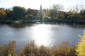 Lake in park in fall and sun reflecting in water