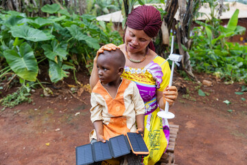 African mother rests her hand on the head of her baby to whom she is lecturing about clean energy
