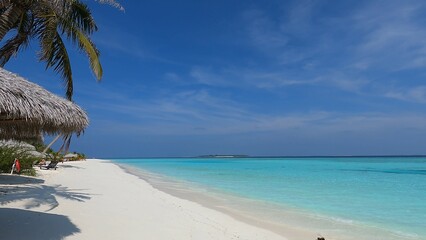Maldives beach, waves wash the shore with white sand, clear azure water, and blue sky. Beauty,...