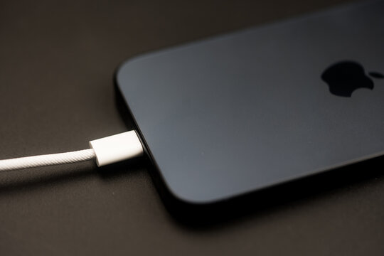 Bangkok, Thailand - November 4, 2023 : Usb type C cable charger a iPhone 15 Pro blue Titanium on a black backgrounda