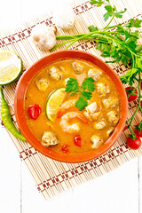 Soup Tom Yum with lime in bowl on board top