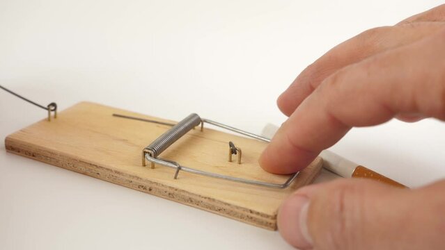 A man sets a trap in a mousetrap in the form of a cigarette. Bad habit concept.