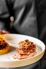 waiter or chef hold Duck fillet with hummus and cherry