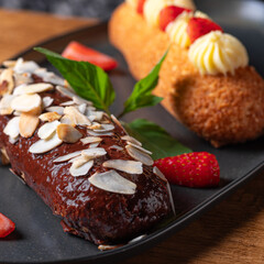 french eclairs set with original cream decor on plate on wooden background. Selective focus.