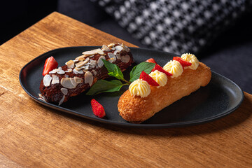 french eclairs set with original cream decor on plate on wooden background. Selective focus.