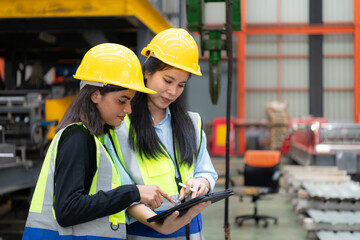 Two female engineers working together in metal sheet factory. This is a freight transportation and distribution warehouse. Industrial and industrial workers concept