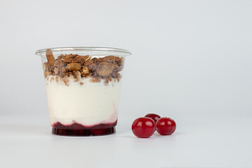 Yogurt with granola flakes and fruits in a plastic cup to go