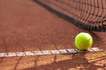 Tennis, ball and clay court, net and line for exercise, training and fitness outdoor in summer. Sports, netting and closeup of sphere on ground for game, competition and workout on field and pitch