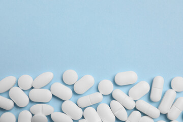 Many pills on light blue background, flat lay. Space for text - obrazy, fototapety, plakaty