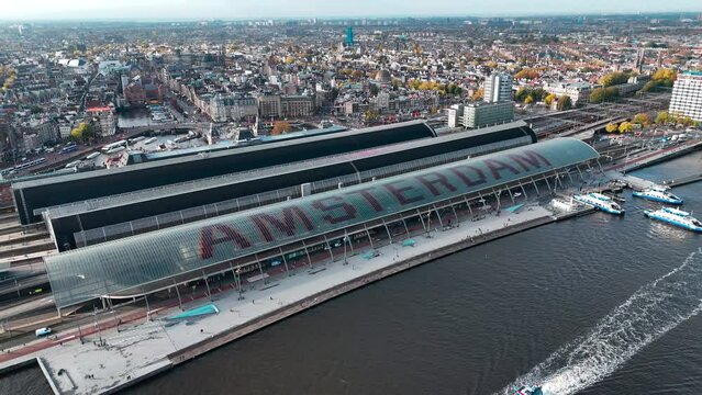 Aerial drone view Amsterdam Central Train Station with Amsterdam sign on roof. Bird's eye view autumn cityscape. High quality 4k footage