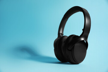 Fototapeta na wymiar Modern wireless headphones on light blue background. Space for text
