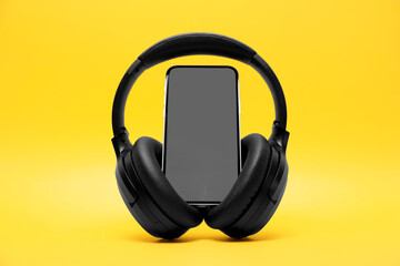 Modern wireless headphones and smartphone on yellow background