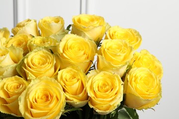 Beautiful bouquet of yellow roses near white wall, closeup
