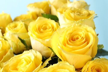 Beautiful bouquet of yellow roses on light blue background, closeup