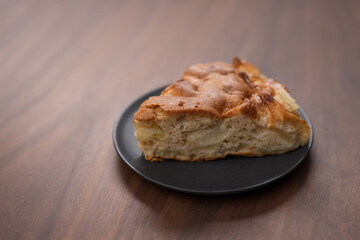 A piece of charlotte apple pie on a saucer on walnut table
