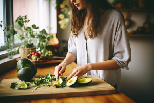Woman cutting avocado on cutting board to prepare breakfast