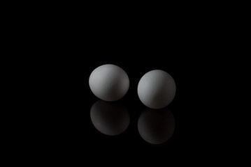 White chicken eggs on black background with reflection