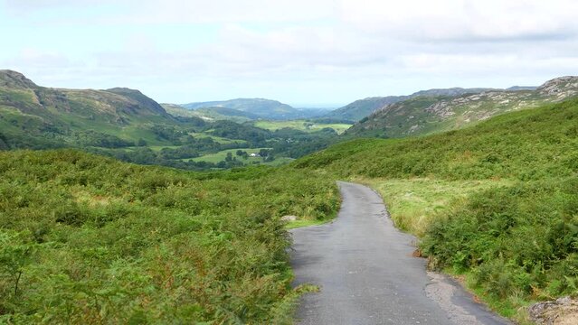 Motorcycle rider with passenger going uphill from Eskdale to Hard Knott Pass, Hardknott Pass in a beautiful mountain scenery of English Lake District.
