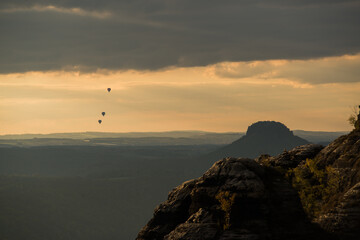 Heißluftballons am Horizont mit Tafelberg im Bild bei farbigem Himmel