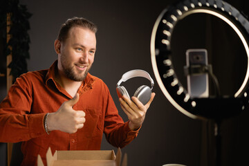 Male techno blogger filming review of new headphones for his channel. Vlogger doing product review...