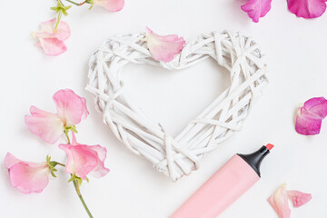 Marker, highlighter, delicate pink leaves, a white weaved heart on white background. Romanic decoration, Love, Valentine’s Day Concept. Copy space, mock up