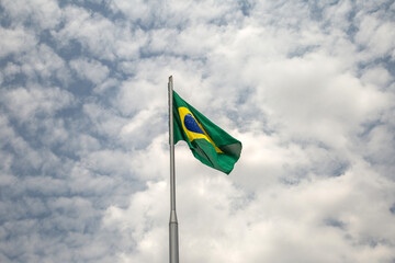 Uma Bandeira do Brasil tremulando ao vento em um dia nublado.