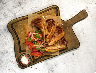 rack of lamb with tomatoes onions and greens sown on a wooden board. selective focus . 