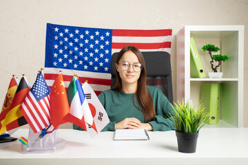Learning at a language school, young woman studying in a class with international flags