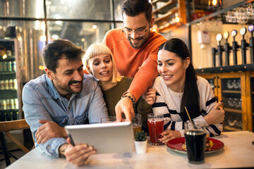 Young friends looking at digital tablet while sitting in cafe.
