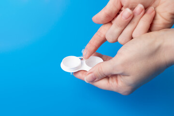 Optical care, transparent lens for astigmatism and eye health in hand with a lenses case