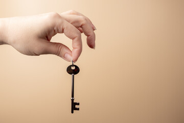 key in hand on a beige background, mortgage, real estate, property insurance, credit and loan