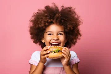 Rolgordijnen diverse girl with curly hair eating a vegan burger or burger on pink background. Restaurant, food delivery website horizontal banner. © Dina