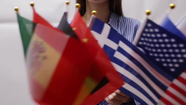 Woman holding different flags in her hands, cultural diversity, global community, international partnership, world peace, multicultural harmony, various national symbols