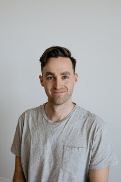 Young man dorky smile grey shirt plain background