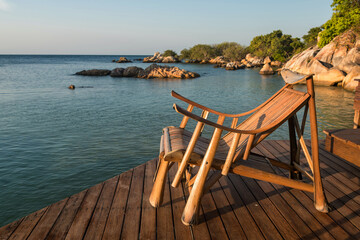 Fototapeta na wymiar Wood sunbed deck at resort patio by sea in morning, Ko Man Klang
