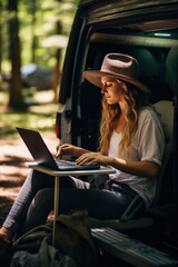 Woman freelancer sits on ground in forest working online on modern laptop against travel car. Remote profession with convenient facilities and flexible schedule to complete tasks.