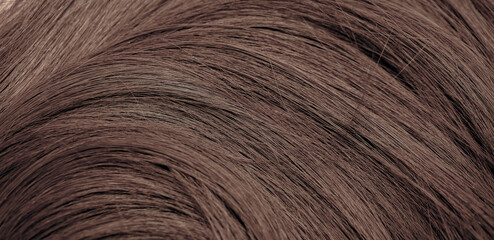 Brown hair close-up as a background. Women's long brown hair. Beautifully styled wavy shiny curls....