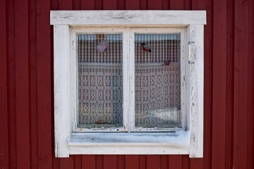 White frame window on the facade of a red painted building.