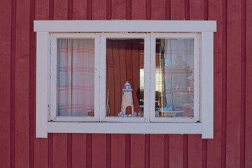 White frame window on the facade of a red painted building.