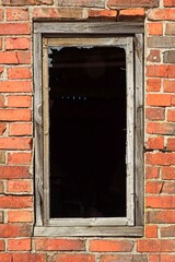 Closeup of damaged window on the wall of an abandoned brick building.