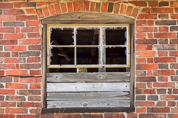 Closeup of damaged window on the wall of an abandoned brick building.